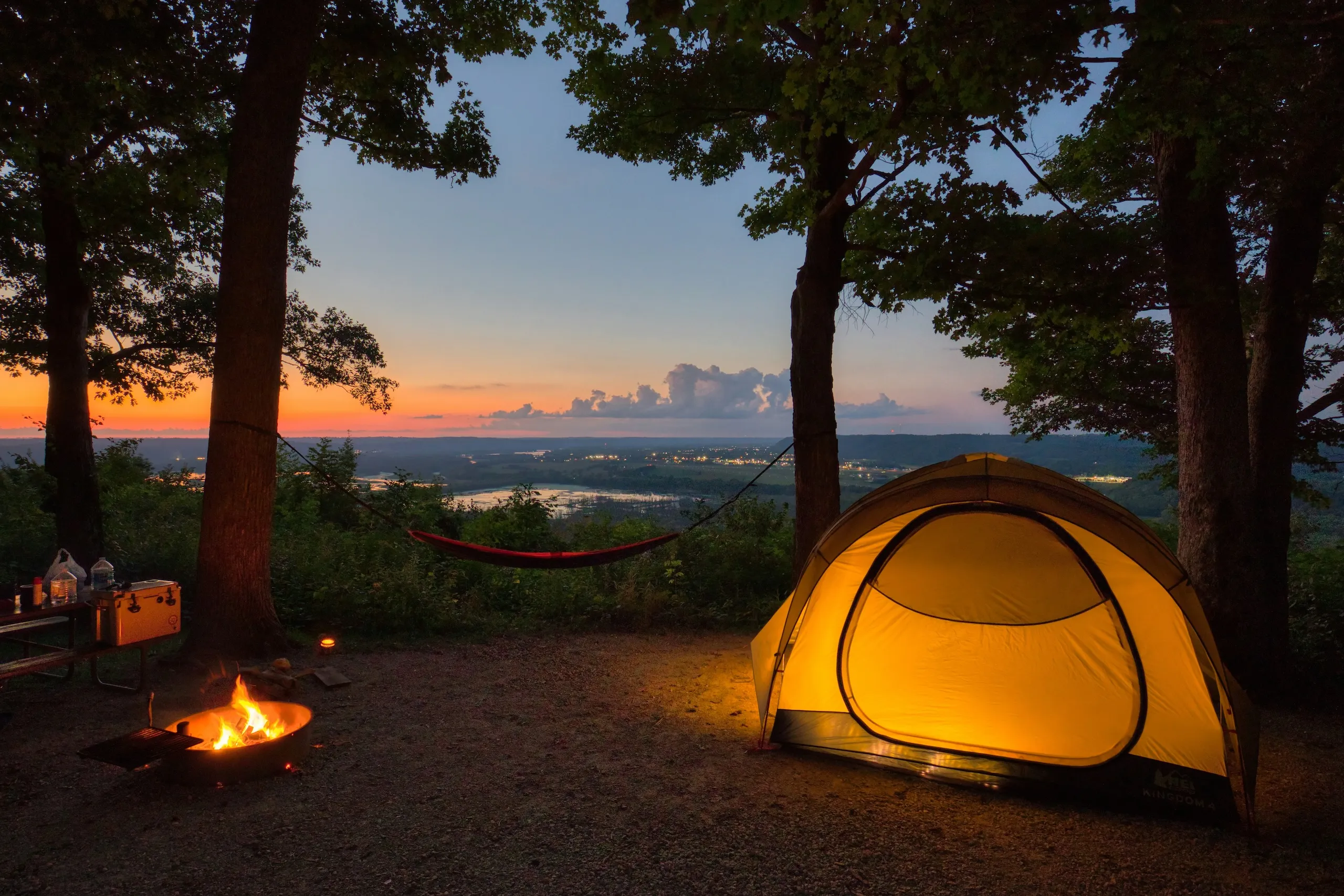 A tent pitched among trees at sunset