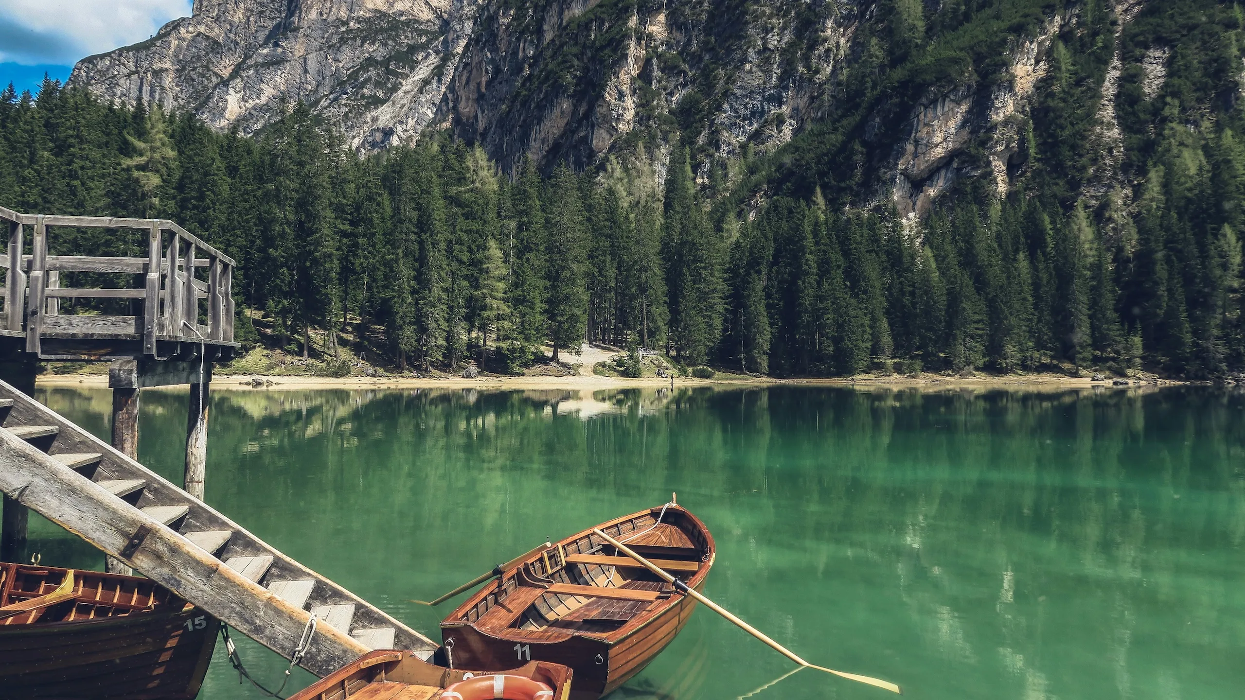 A wooden canoe tied to a grey timber dock at a calm waterway